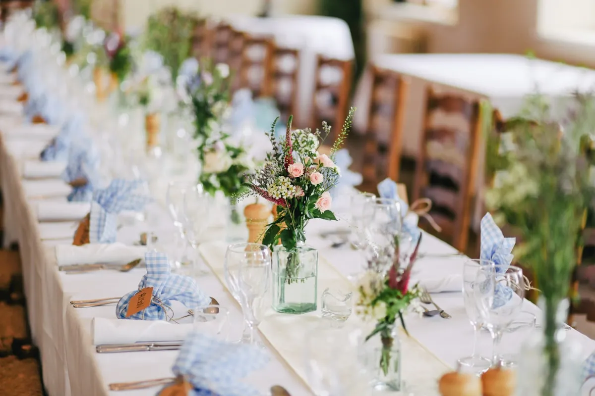 Mesa de recepção posta com arranjos de flores e taças
